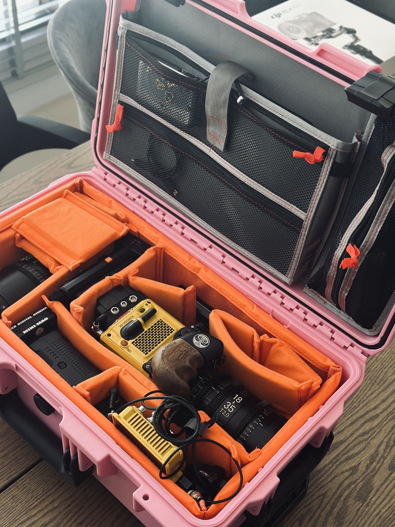 Pink case open, a camera and lenses packed into orange dividers