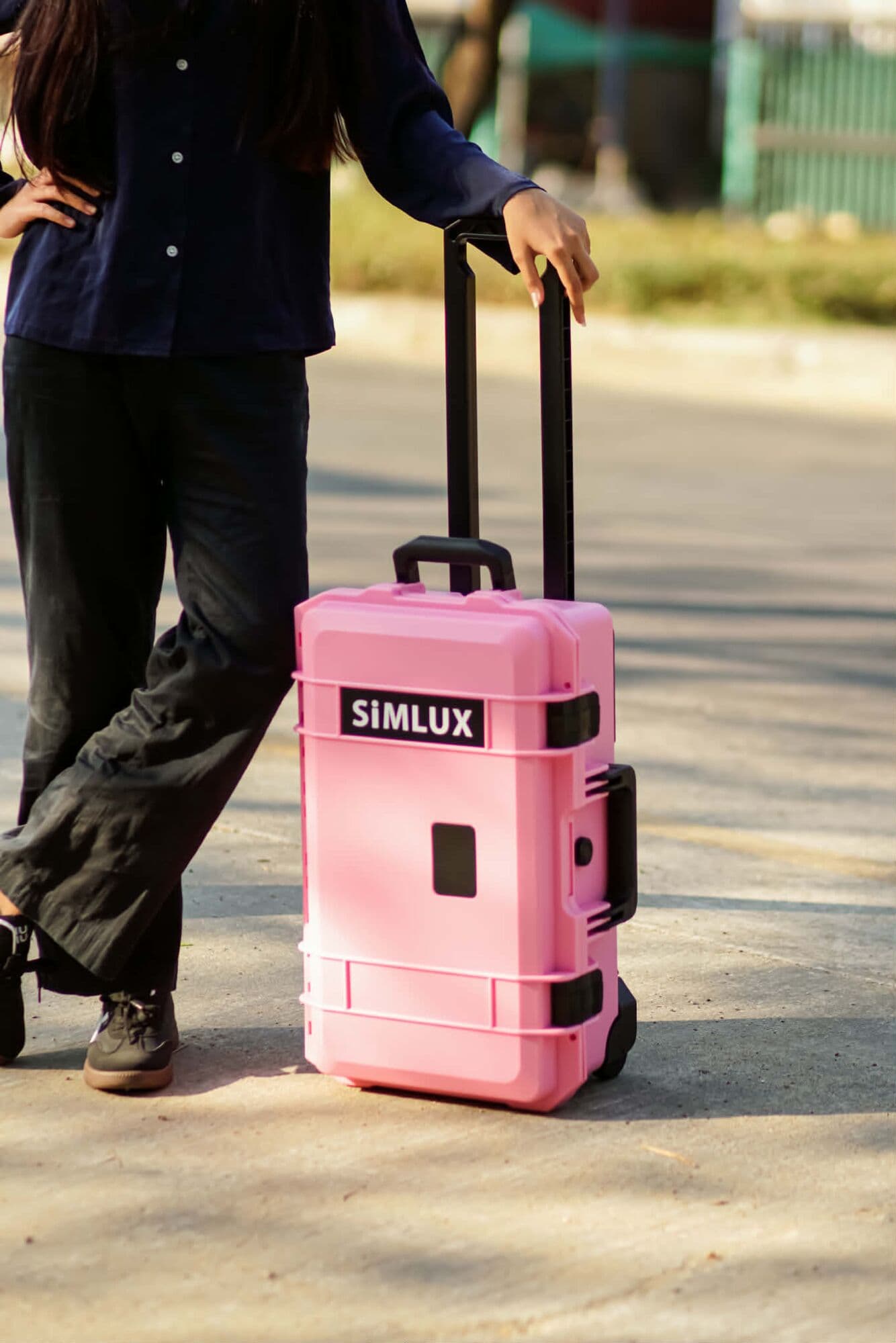 Model wheeling a Pink SiMLUX Professional Protection Case down a sunny street